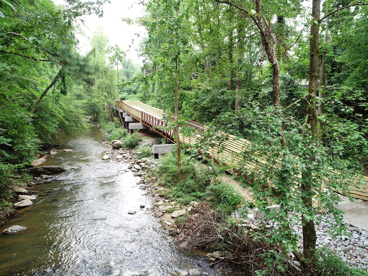 The trail stretches across a small body of water with surrounded trees.