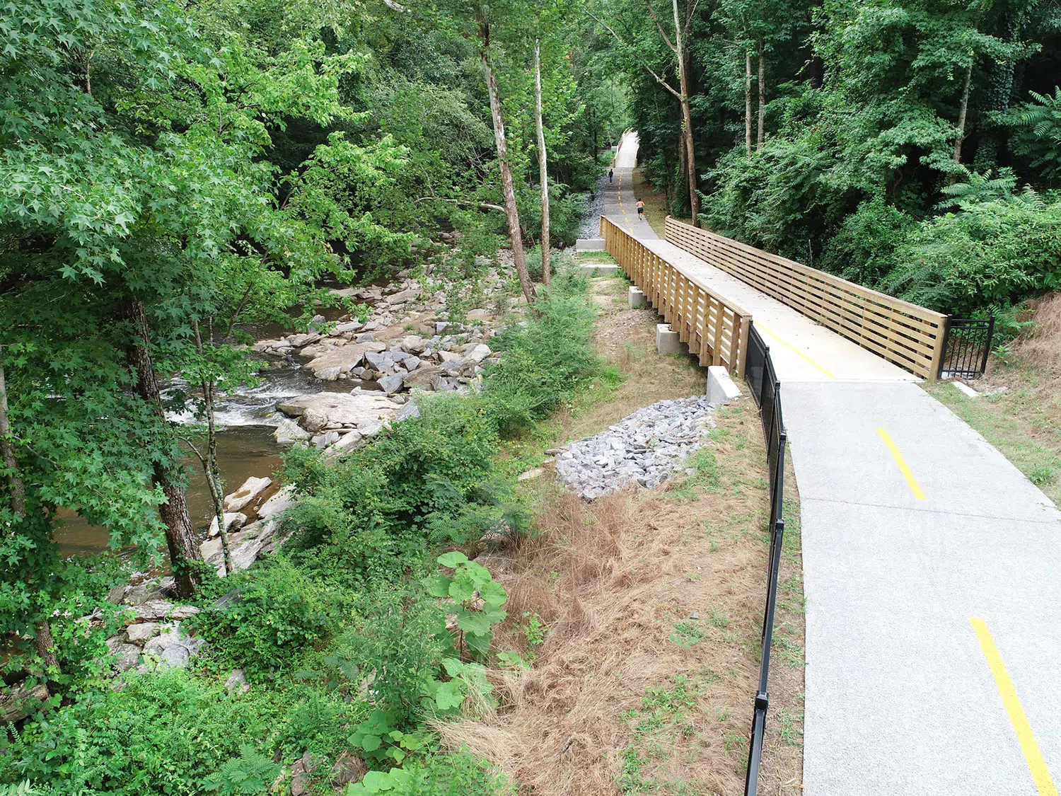 The bridge, which is a part of the trail, disappears into a wall of trees.