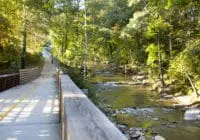 The trail runs by a small body of water with trees surrounding the trail.