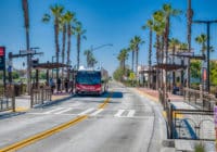 A Rapid bus picks up riders at a bus station along the road.