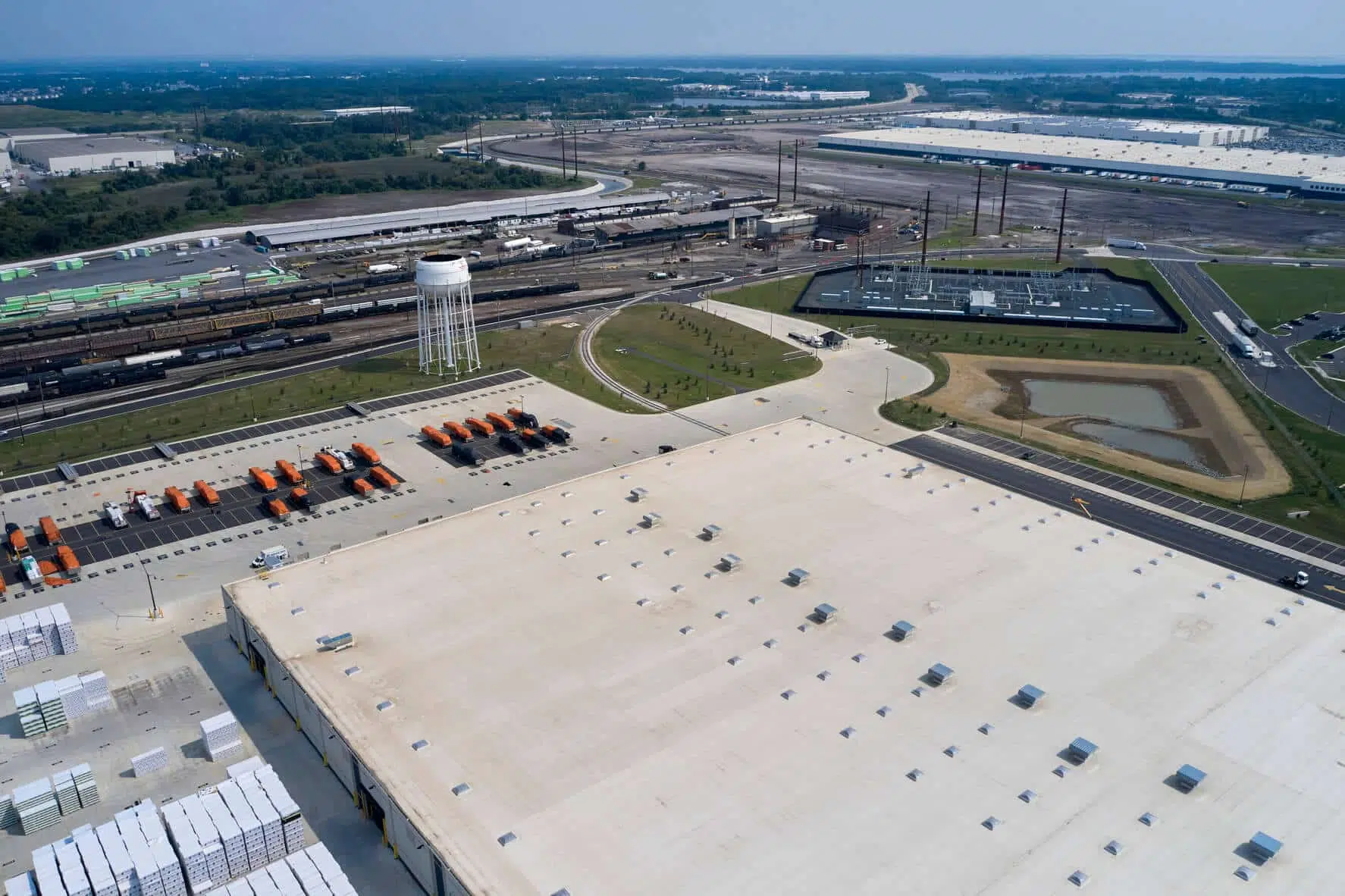 Overlooking the back corner of the warehouse where there is a pond and a water tower.