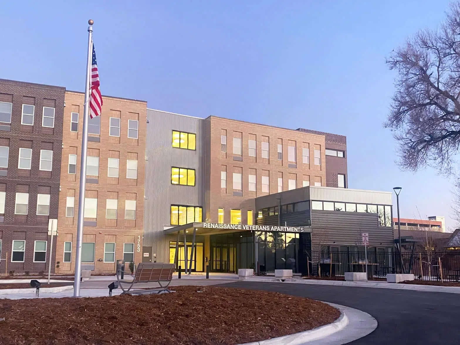 The entrance to the Fitzsimons Veterans Apartments with an American Flag raised on a pole