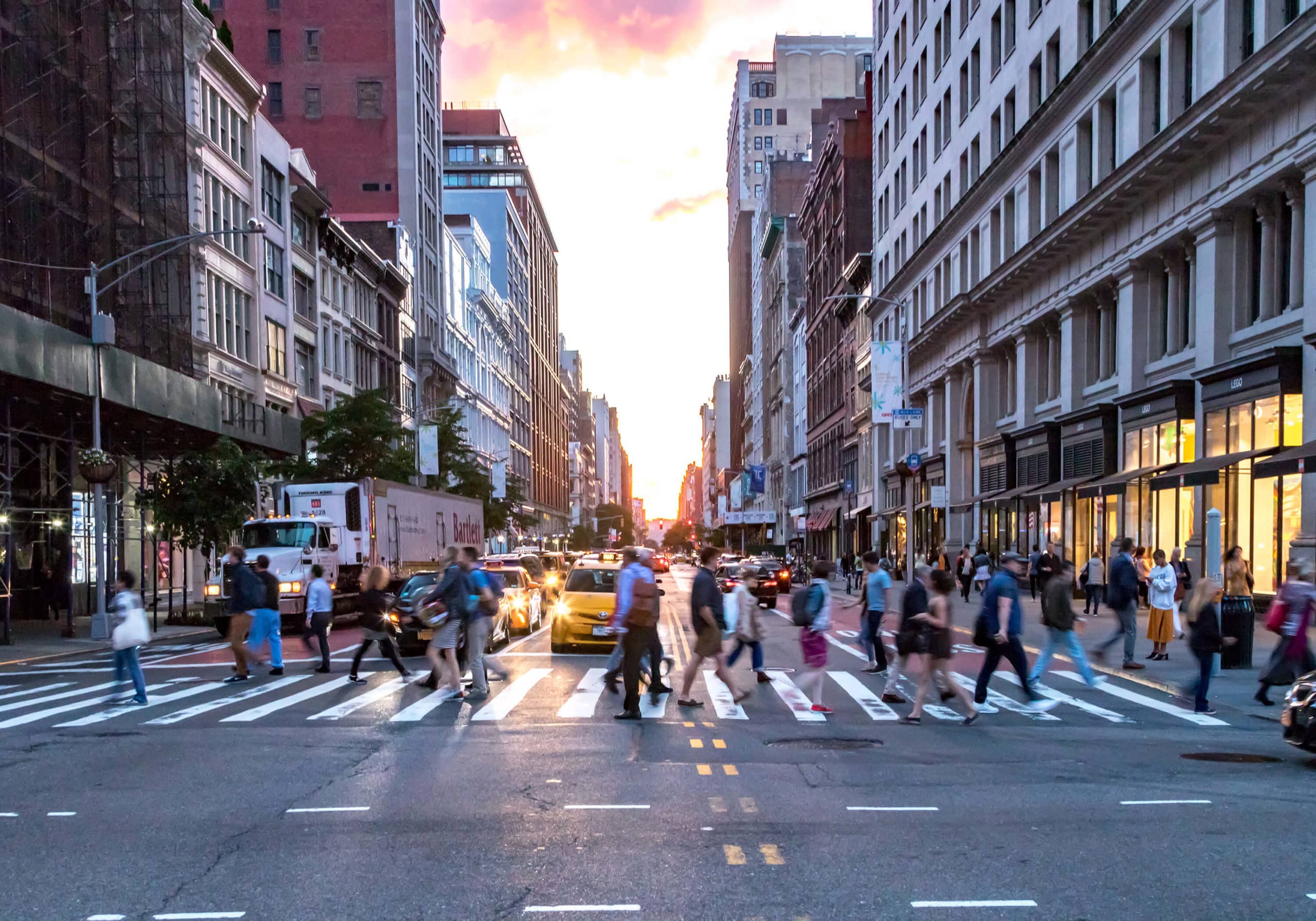 People in a busy city walking across a crosswalk