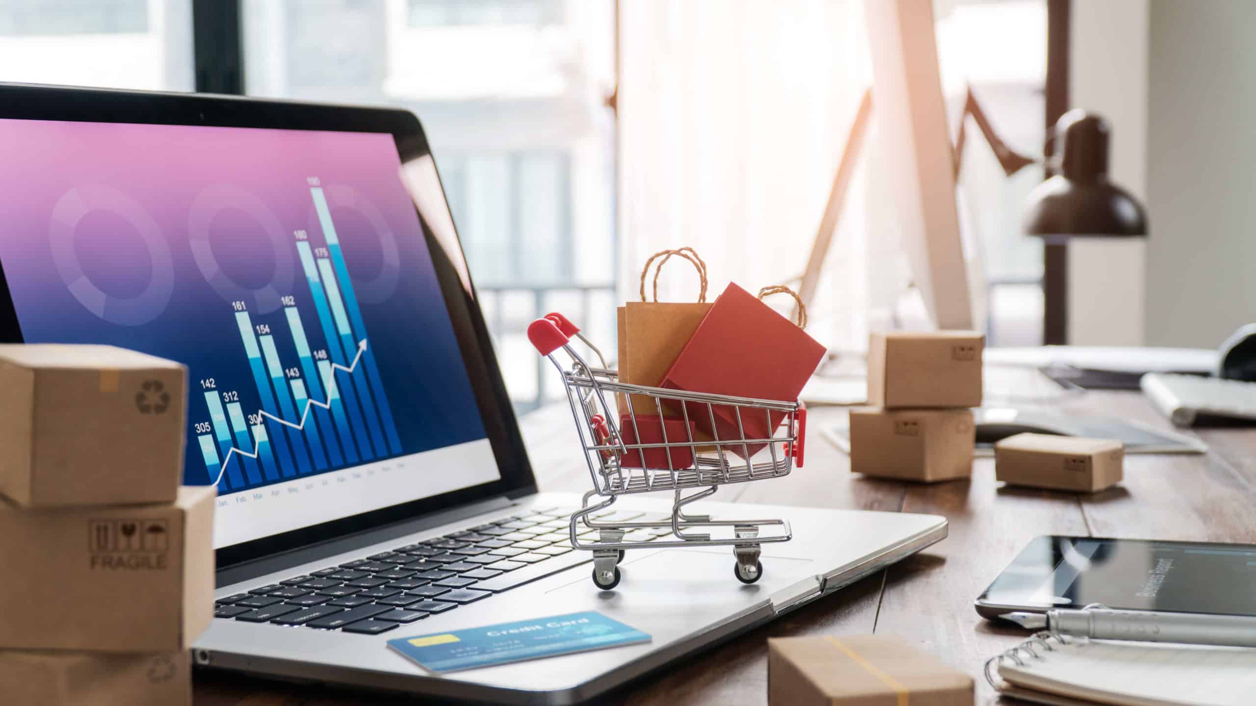 A small shopping cart full of bags on top of a laptop