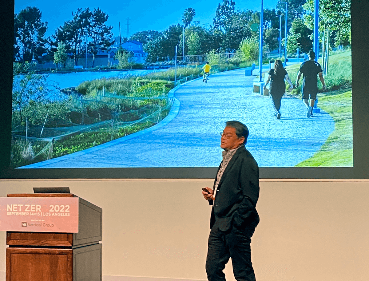 Gary Lai presenting the topic od sustainability in front of an image of a walking trail